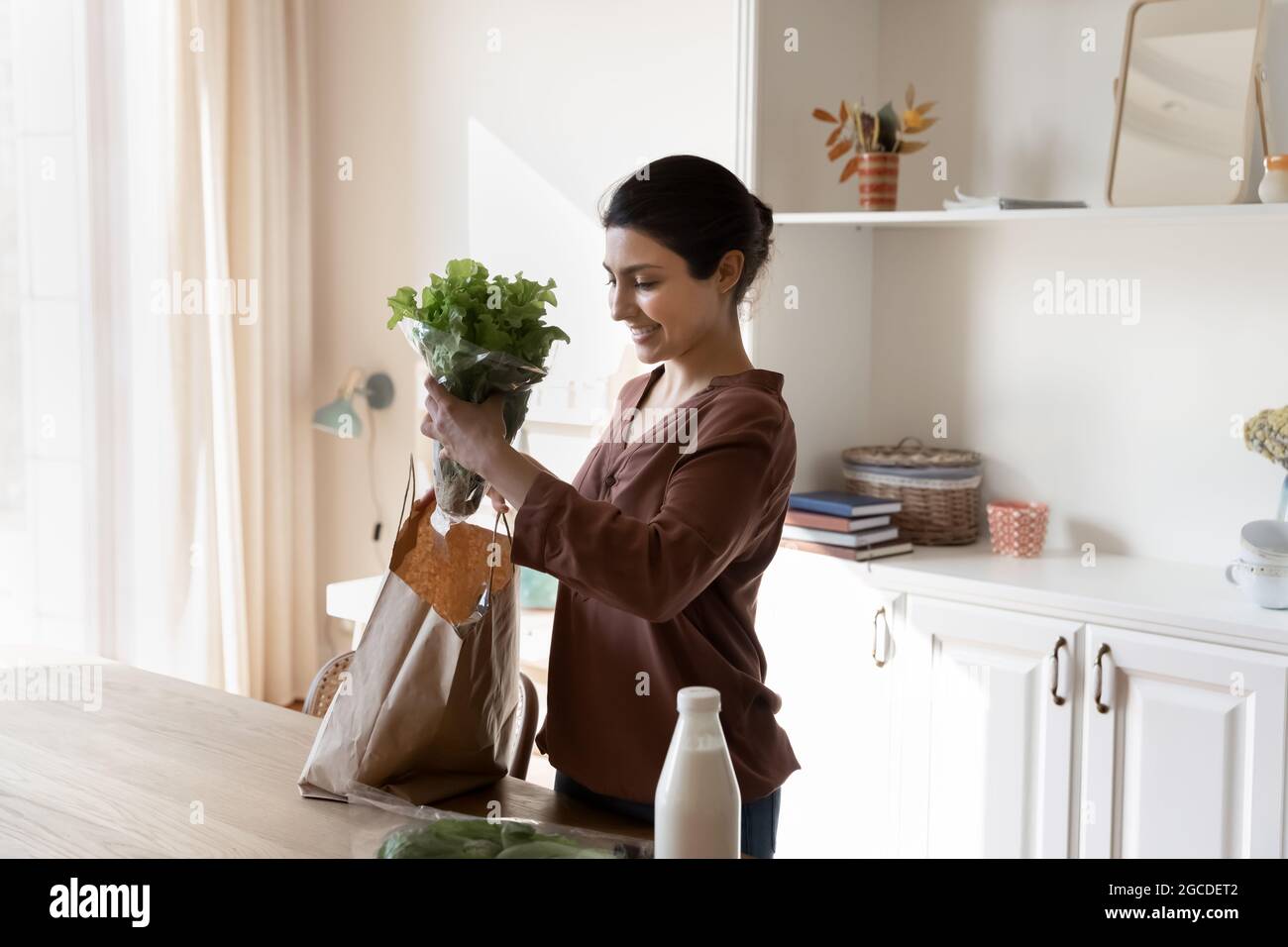 Donna indiana sorridente scompattare la borsa con i prodotti Foto Stock