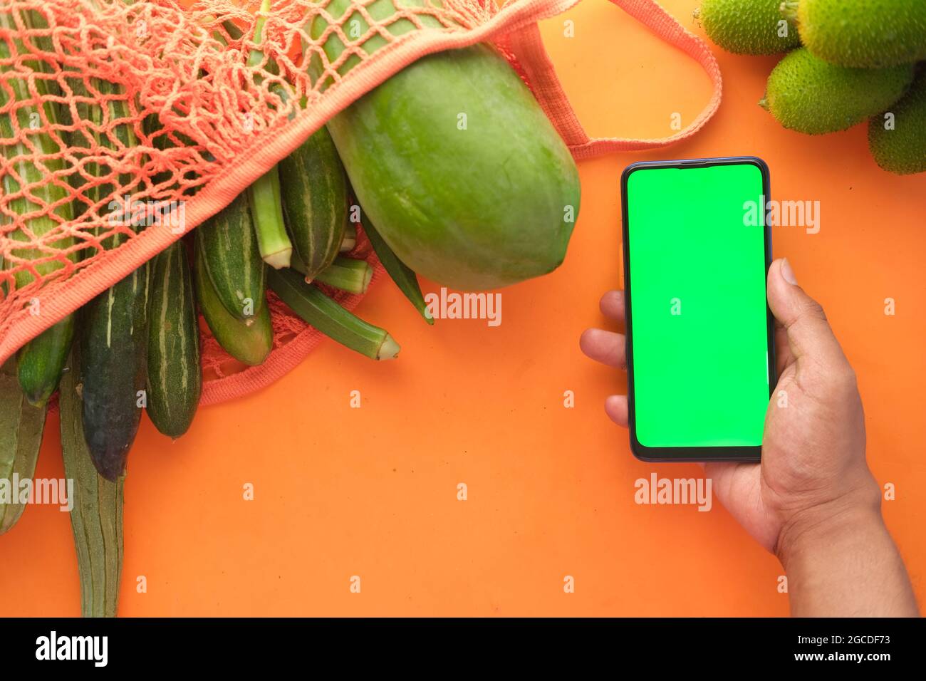 vista dall'alto dello smartphone uomo che tiene le mani con fresh verdure sul tavolo Foto Stock