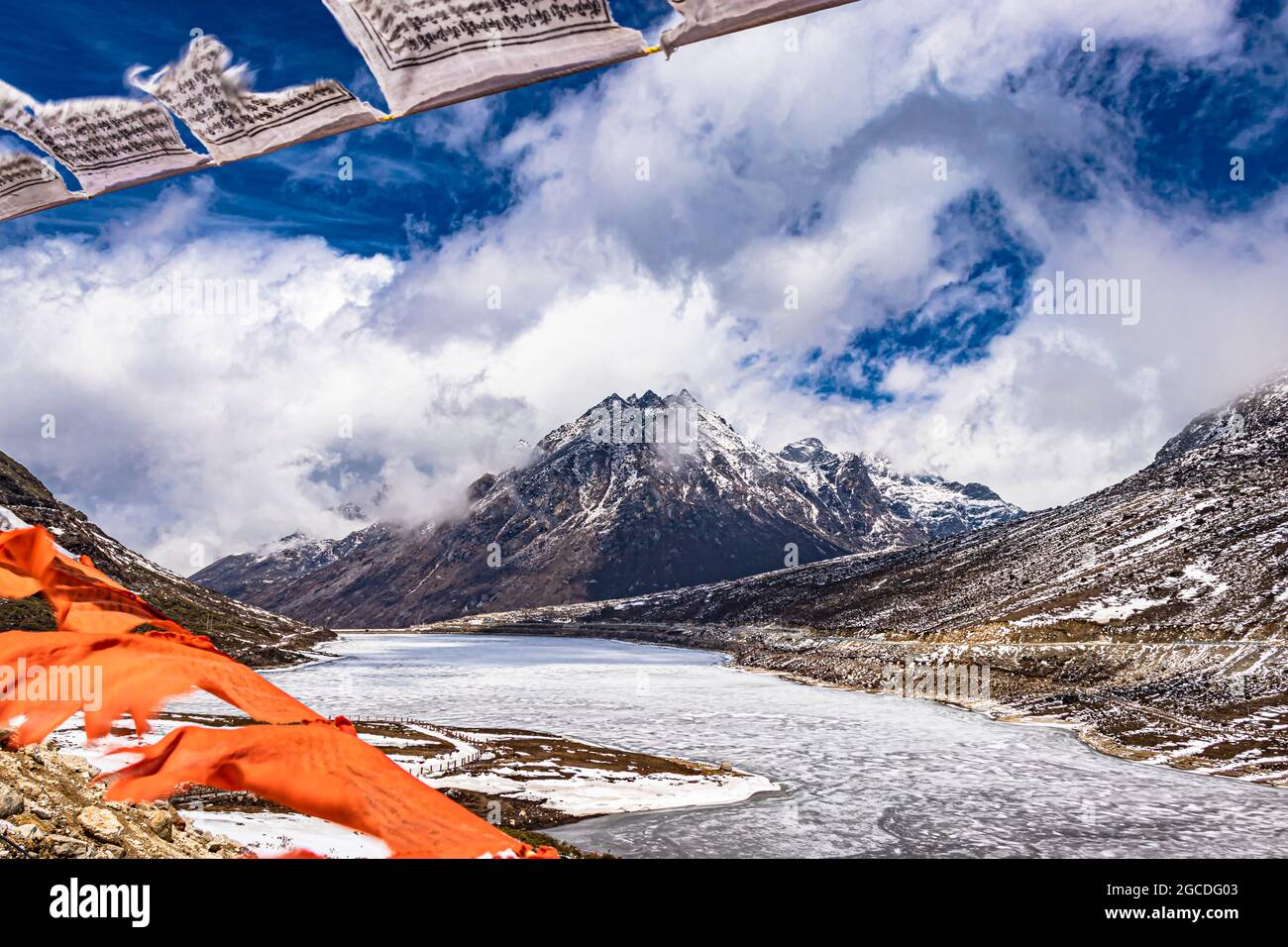 montagna con copertura della neve con cielo drammatico attraverso il blurred buddismo bandiere cornice al giorno l'immagine è presa al passo di sela tawang arunachal pradesh india. Foto Stock
