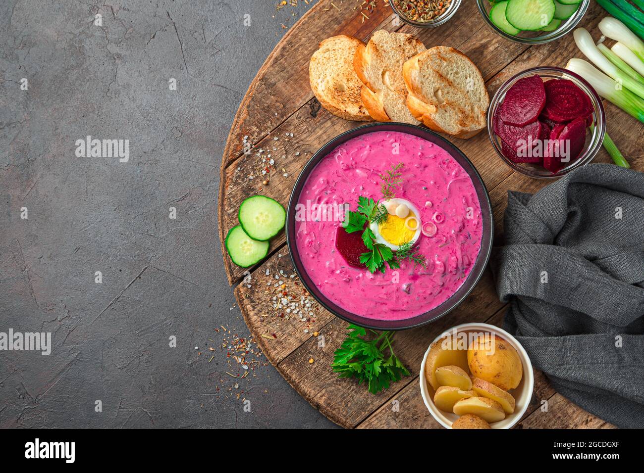 Zuppa di barbabietole su sfondo scuro. Piatto vegetariano freddo di barbabietole, patate, cetrioli, uova, cipolle verdi, aneto e prezzemolo con kefir o acidia Foto Stock