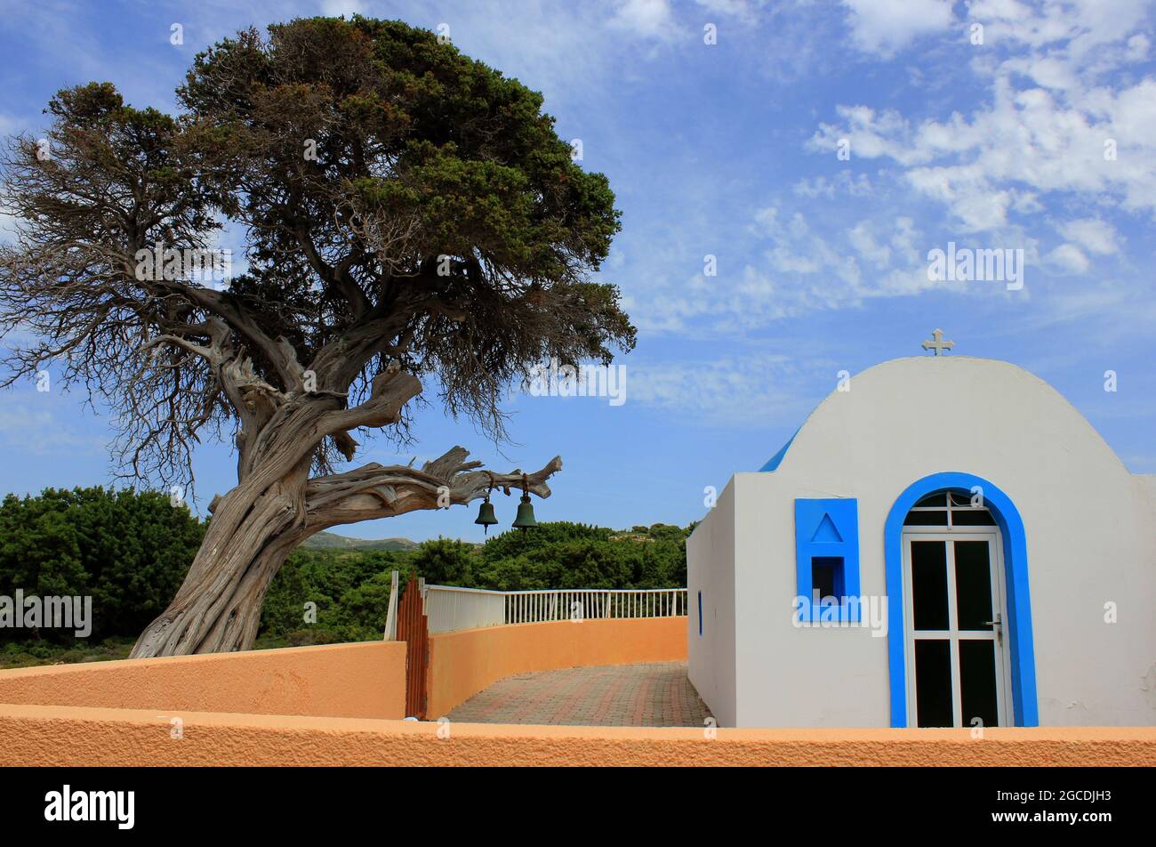 In völliger Abgeschiedenheit stehende kleine griechische Kapelle auf der Insel Kos, mit einem Majestätische Baum an dem 2 Kirchenglocken hängen Foto Stock