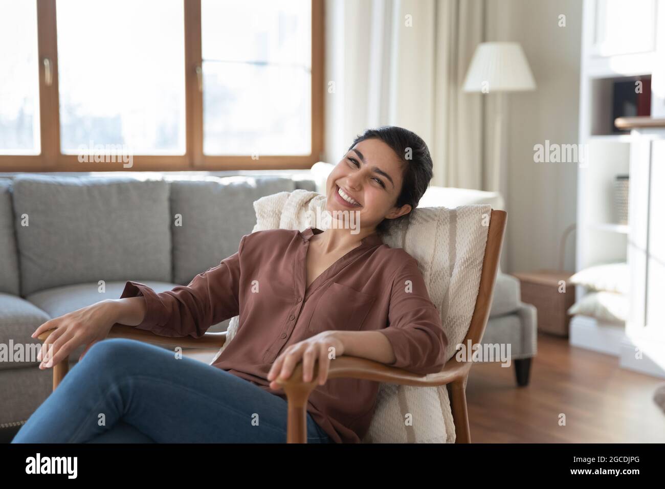Ritratto di felice donna indiana rilassarsi in comoda poltrona Foto Stock