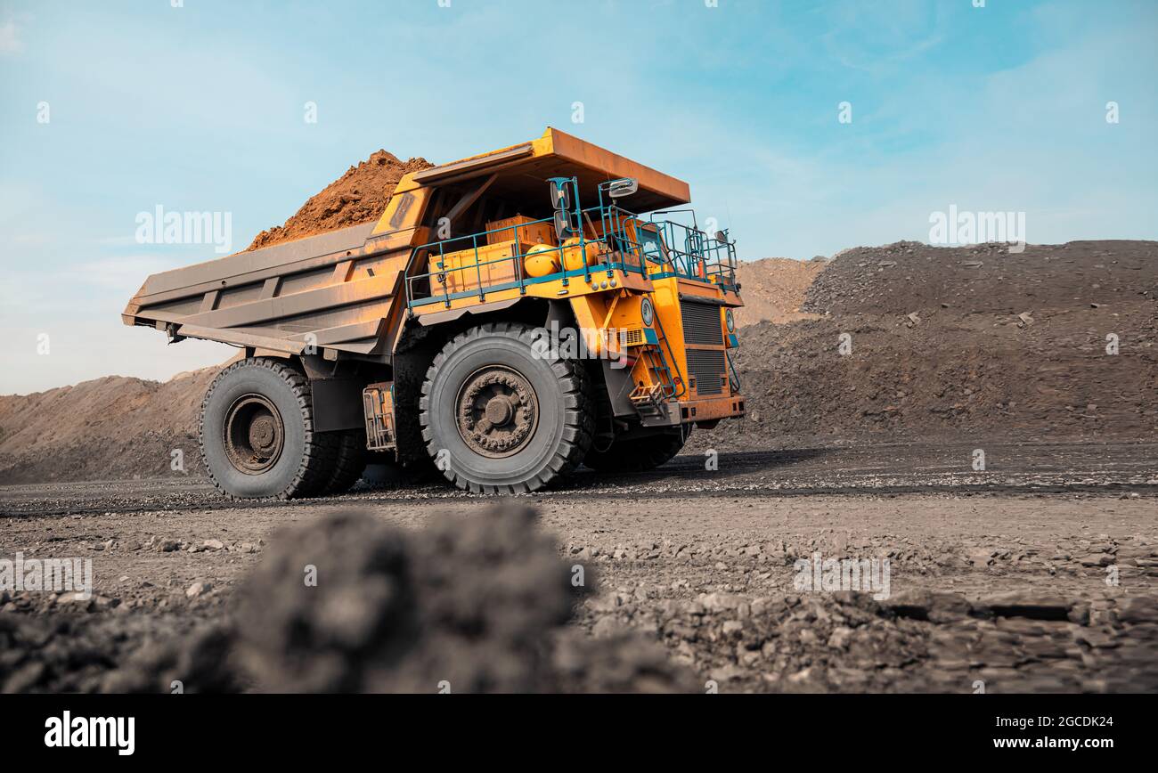 Dumper da cava di grandi dimensioni. Grande dumper da miniera giallo sul luogo di lavoro. Caricamento del carbone nel camion della carrozzeria. Produzione di minerali utili. Macchinari per attività estrattive di autocarri Foto Stock