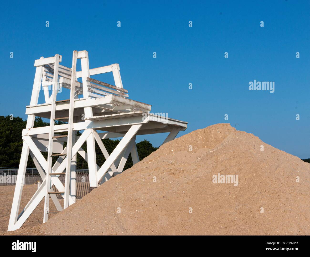 Il bagnino bianco si trova di fronte a un mucchio di sabbia e il cielo blu sopra il Sunken Meadow state Park al mattino. Foto Stock