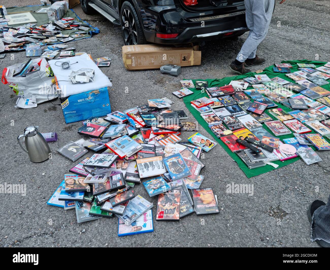 Exeter, UK - Agosto 2021: Un giovane uomo caucasico che vende un gran numero di DVD, CD, video-giochi e altri articoli in una vendita di stivali per auto nel Regno Unito Foto Stock