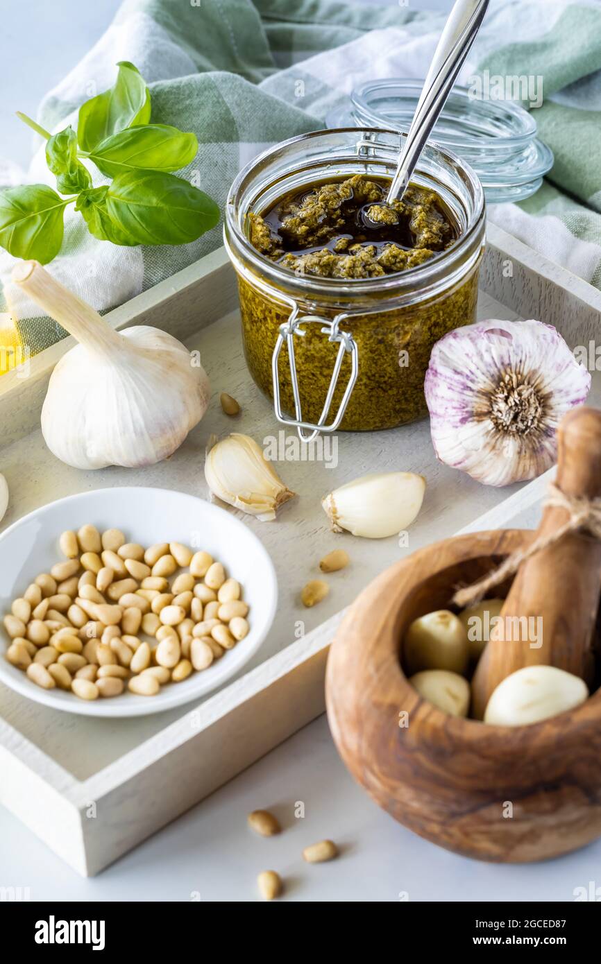 Un vasetto di pesto in un vassoio con tutti gli ingredienti utilizzati per preparare il pesto. Foto Stock