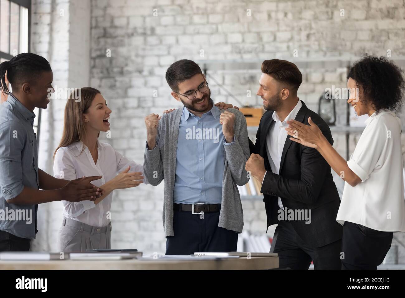 I dipendenti multietnici si congratulano con i colleghi di sesso maschile con la promozione Foto Stock