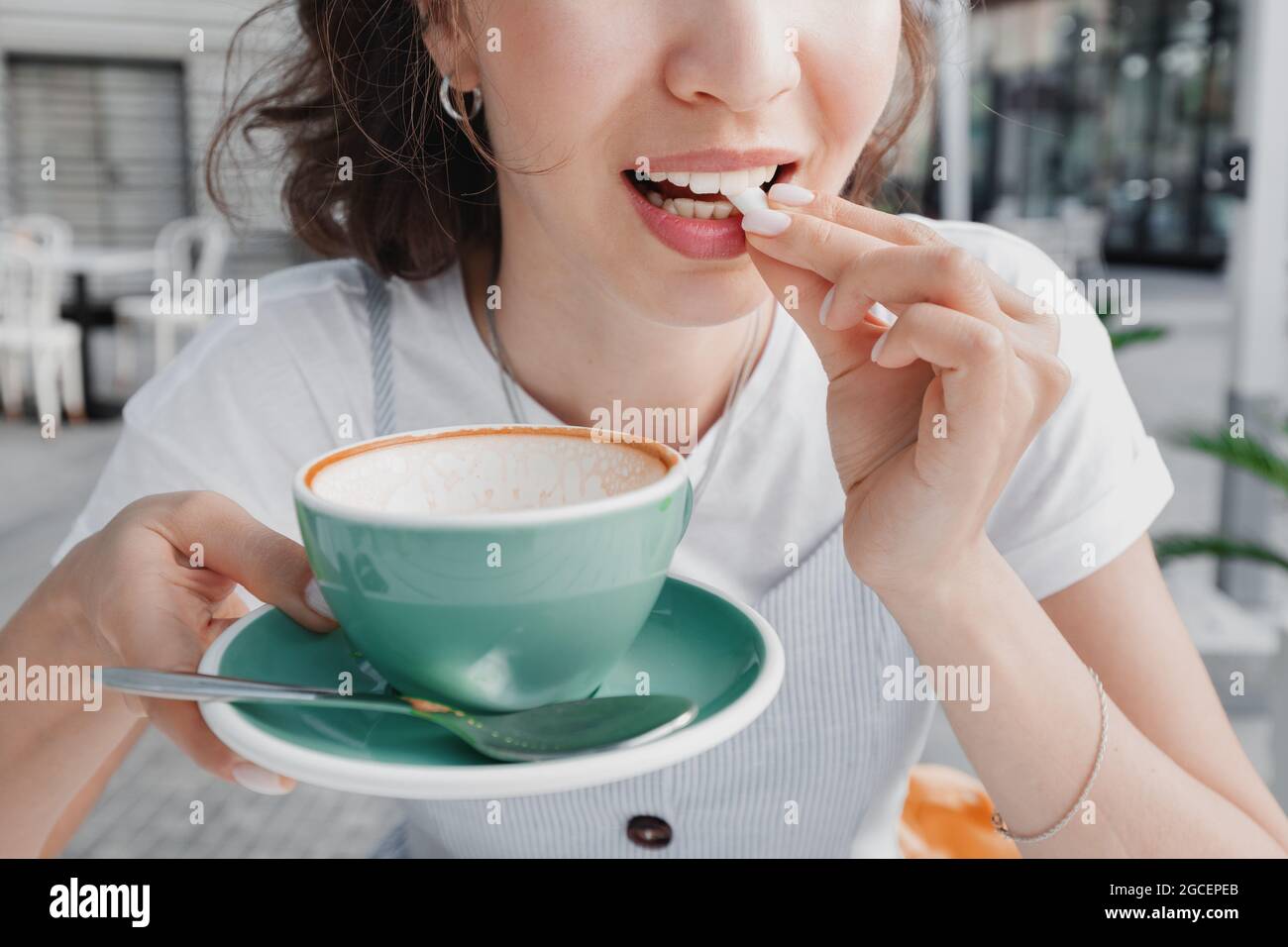 La donna ha finito il suo caffè e sta per masticare la gomma per pulire i denti dalla placca e rinfrescare il respiro. Concetto di salute dentale Foto Stock
