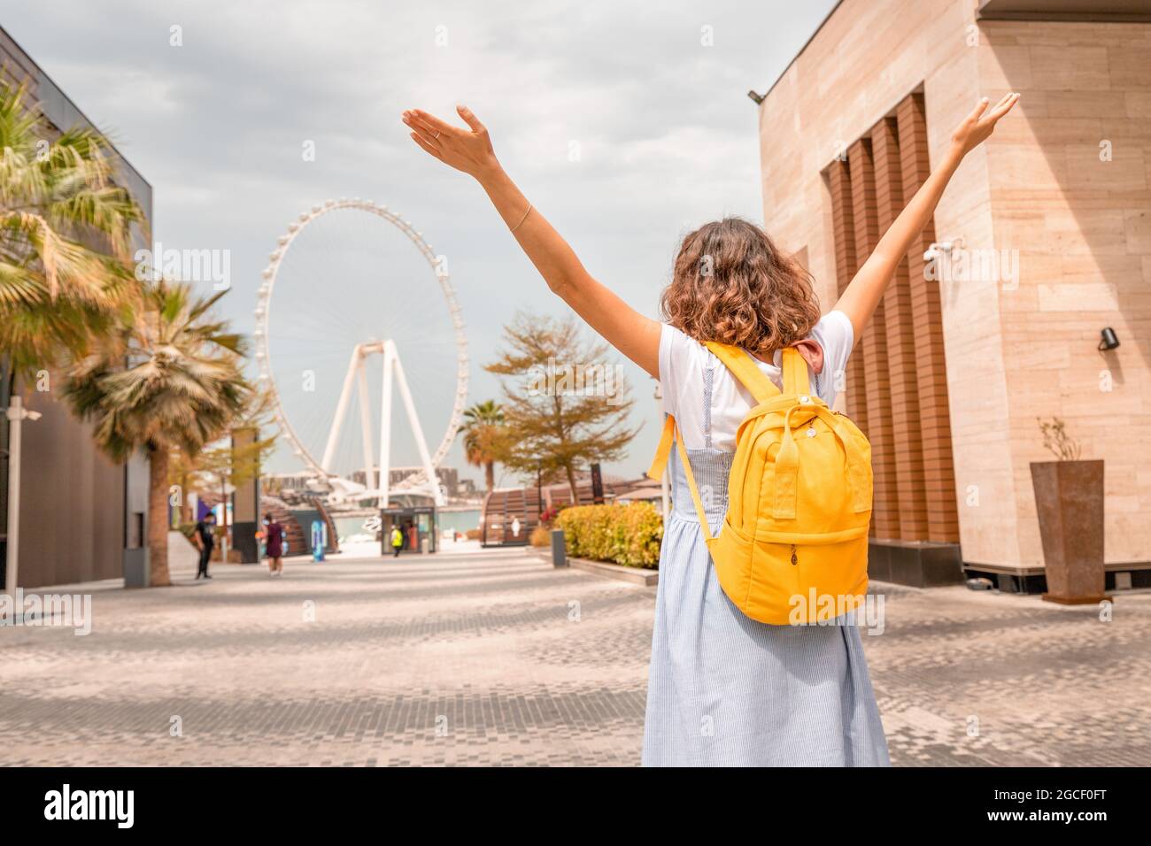 La donna ha gettato le mani in delizia alla vista della ruota panoramica più grande del mondo - Dubai Eye. Principali attrazioni turistiche e visite turistiche in Foto Stock