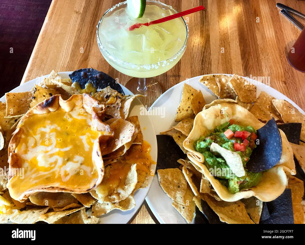 Una margarita ghiacciata e deliziosi antipasti di formaggi e salse di guacamole, serviti in ciotole a conchiglia di taco, con patatine di mais blu e giallo. Foto Stock