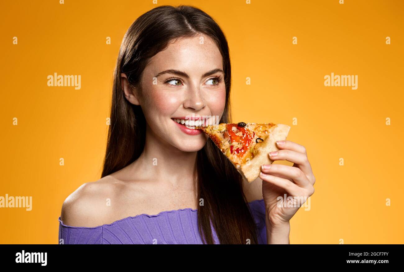 Sorridente ragazza che mangia pizza, mordicchiando fetta e guardando da  parte soddisfatto, provando cibo gustoso, concetto di ordine da asporto in  pizzeria, mangiare fuori dentro Foto stock - Alamy