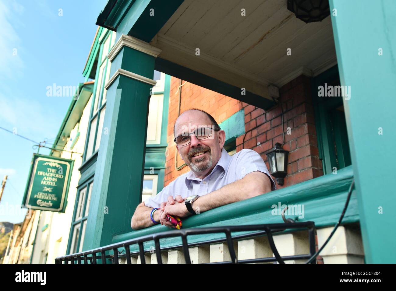 Llanymynech il villaggio che si trova a cavallo tra Inghilterra e Galles. Bob Hedley il padrone di casa dei Bradford Arms appoggiandosi sul suo portico che è in Galles mentre il suo pub è in Inghilterra. Foto Stock