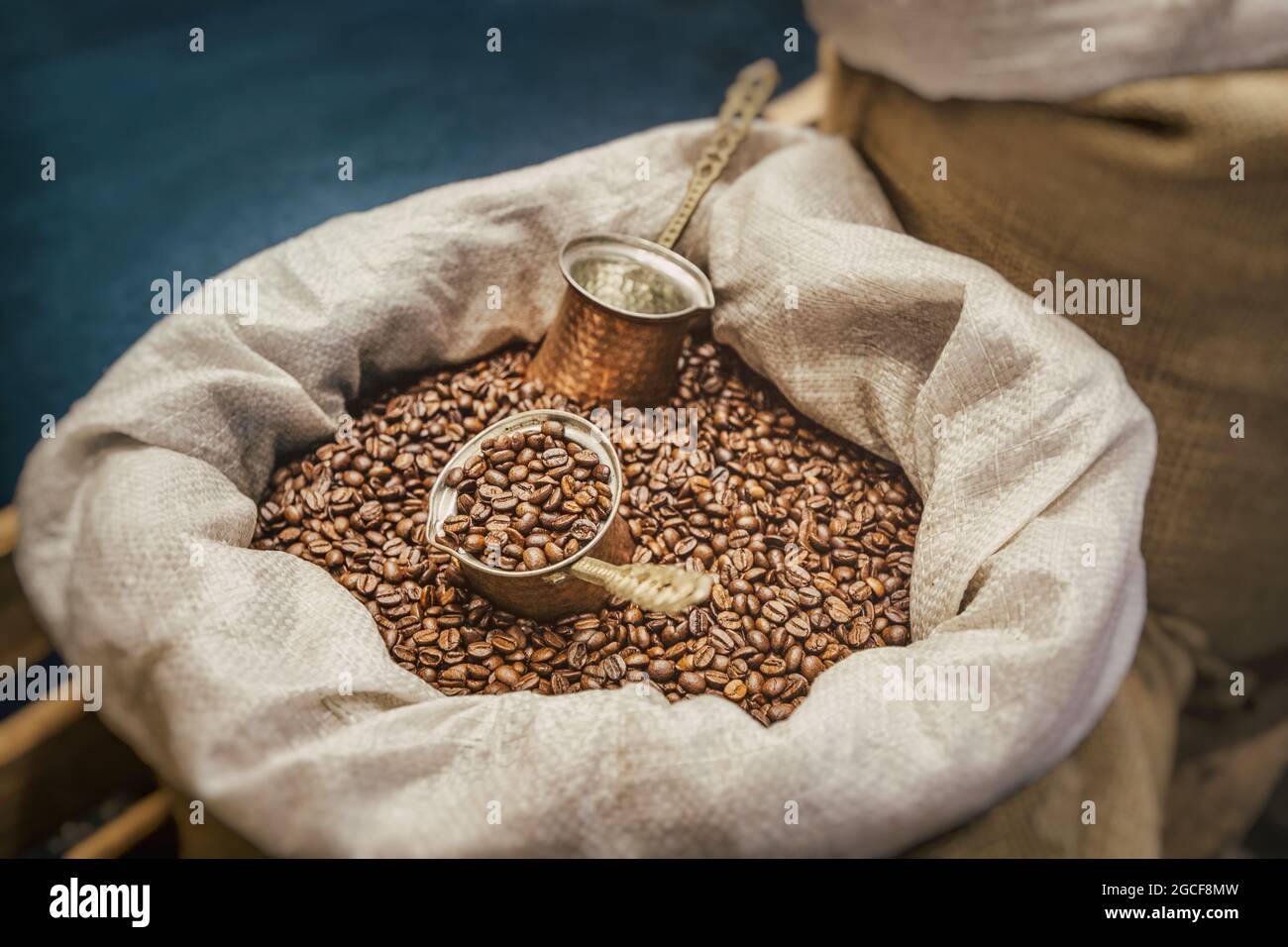 I chicchi di caffè e una macchina per il caffè turco cezve si trovano in una borsa di tela. Il concetto di una bevanda profumata e la sua raccolta Foto Stock