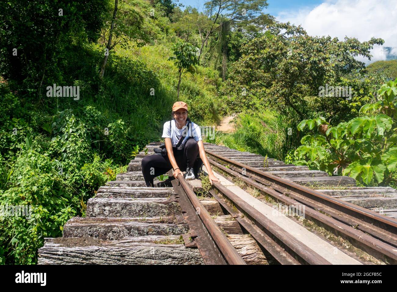 Amaga, Antioquia, Colombia - Luglio 18 2021: Donna Latina nervosa con un lotto di paura cerca di camminare e passare attraverso il Ponte della Ferrovia rustica Vecchia Foto Stock