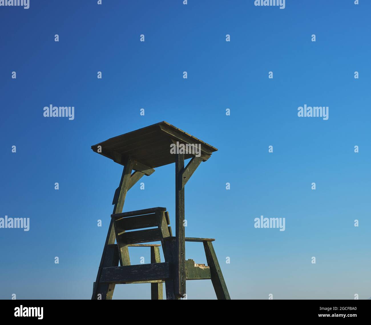 particolare di una sedia di bagnino in legno su una spiaggia con cielo blu Foto Stock