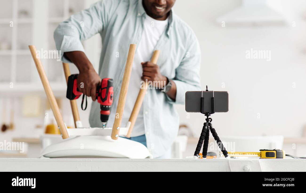 Manuale blogger video istruzioni per assemblare mobili a casa con le proprie mani, utilizzando trapano elettrico, raccolto. Uomo che fa sedia, avvitamento d Foto Stock