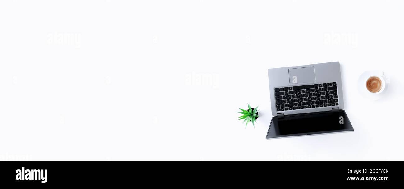 Vista dall'alto su un notebook grigio sottile isolato, una tazza bianca di caffè espresso, una pentola verde con piante di casa su sfondo bianco. Banner wi Foto Stock