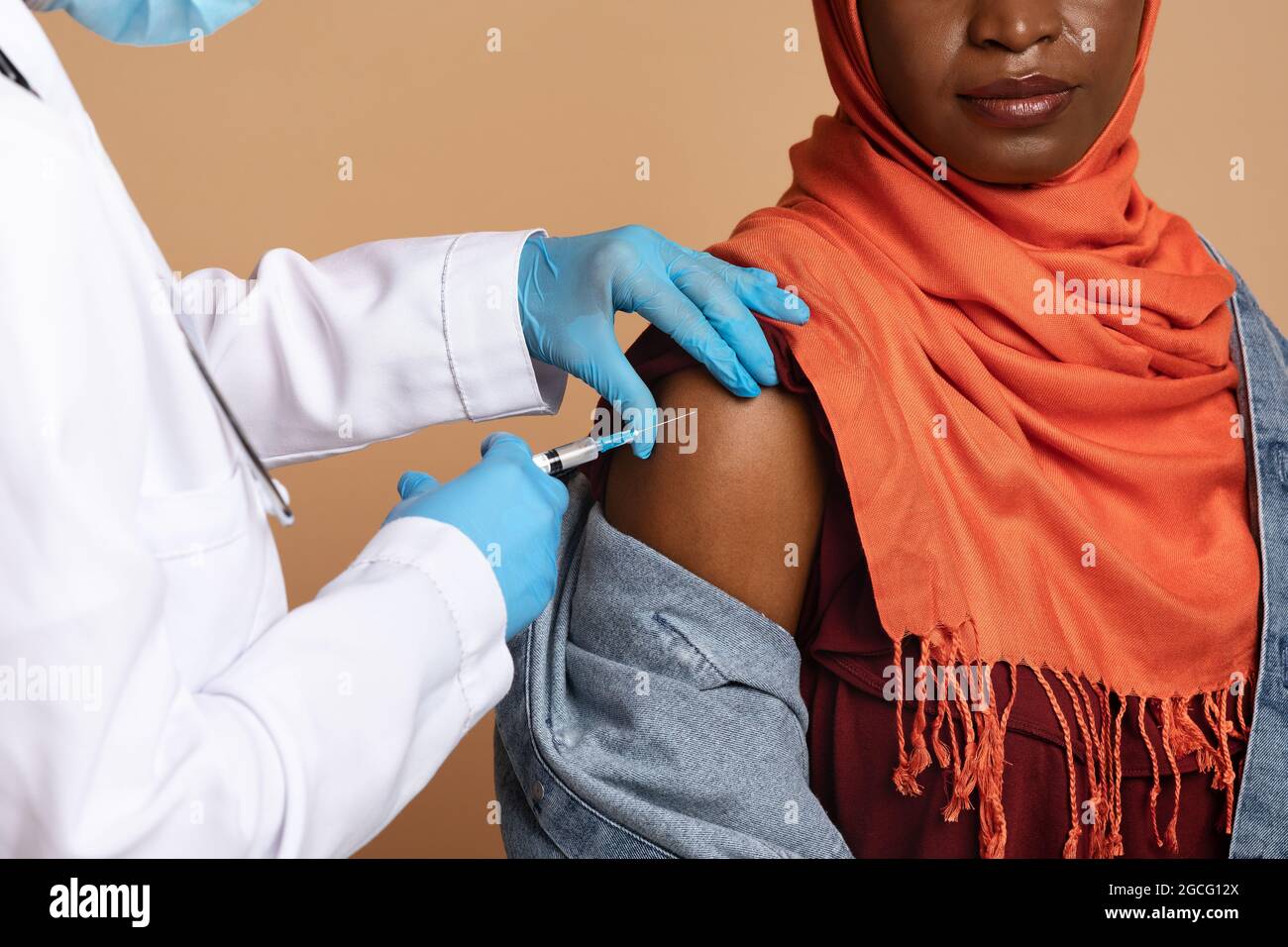 Closeup delle mani dell'infermiere in guanti medici protettivi facendo  l'iniezione intramuscolare nella spalla per la donna nera musulmana, foto  di closeup. Vaccinazione, imm Foto stock - Alamy