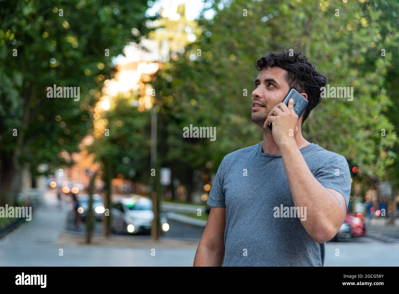 Giovane latino in città che parla con il cellulare. Foto Stock