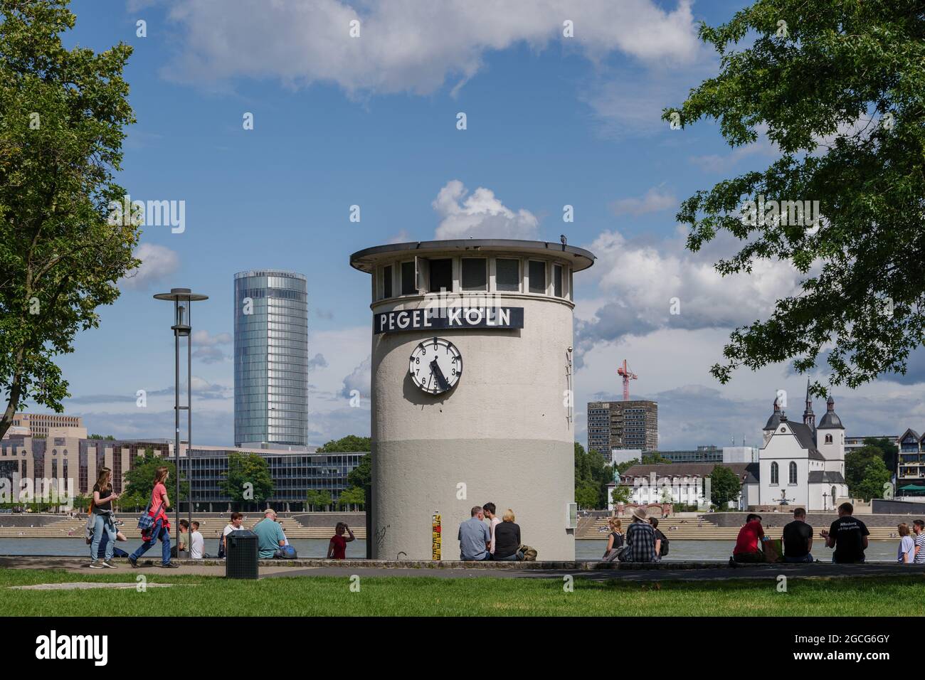 Vista soleggiata all'aperto di Pegelturm, della Torre di Pegel e della gente si siedono intorno al Giardino del Reno lungo il fiume Reno a Colonia, in Germania. Foto Stock