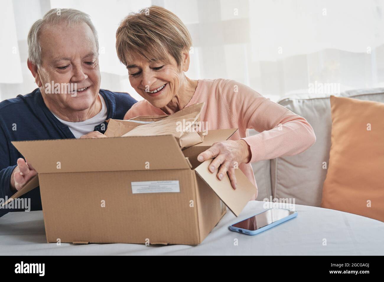 Felice pacchetto di apertura coppia senior ricevuto dalla consegna online a casa - Focus sul volto uomo Foto Stock