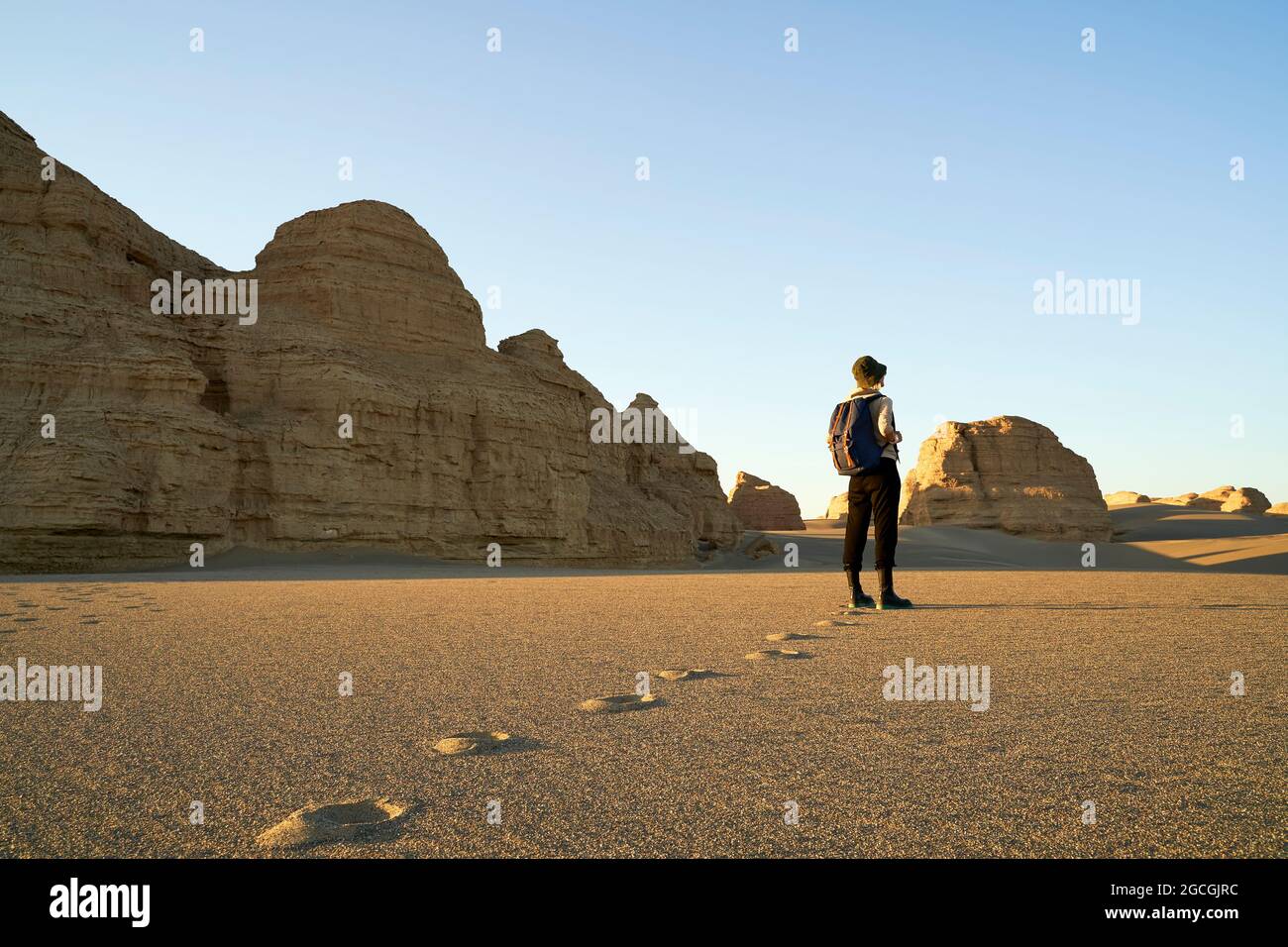 donna asiatica viaggiatore con zaino in piedi nel deserto guardando la forma yardang. Foto Stock