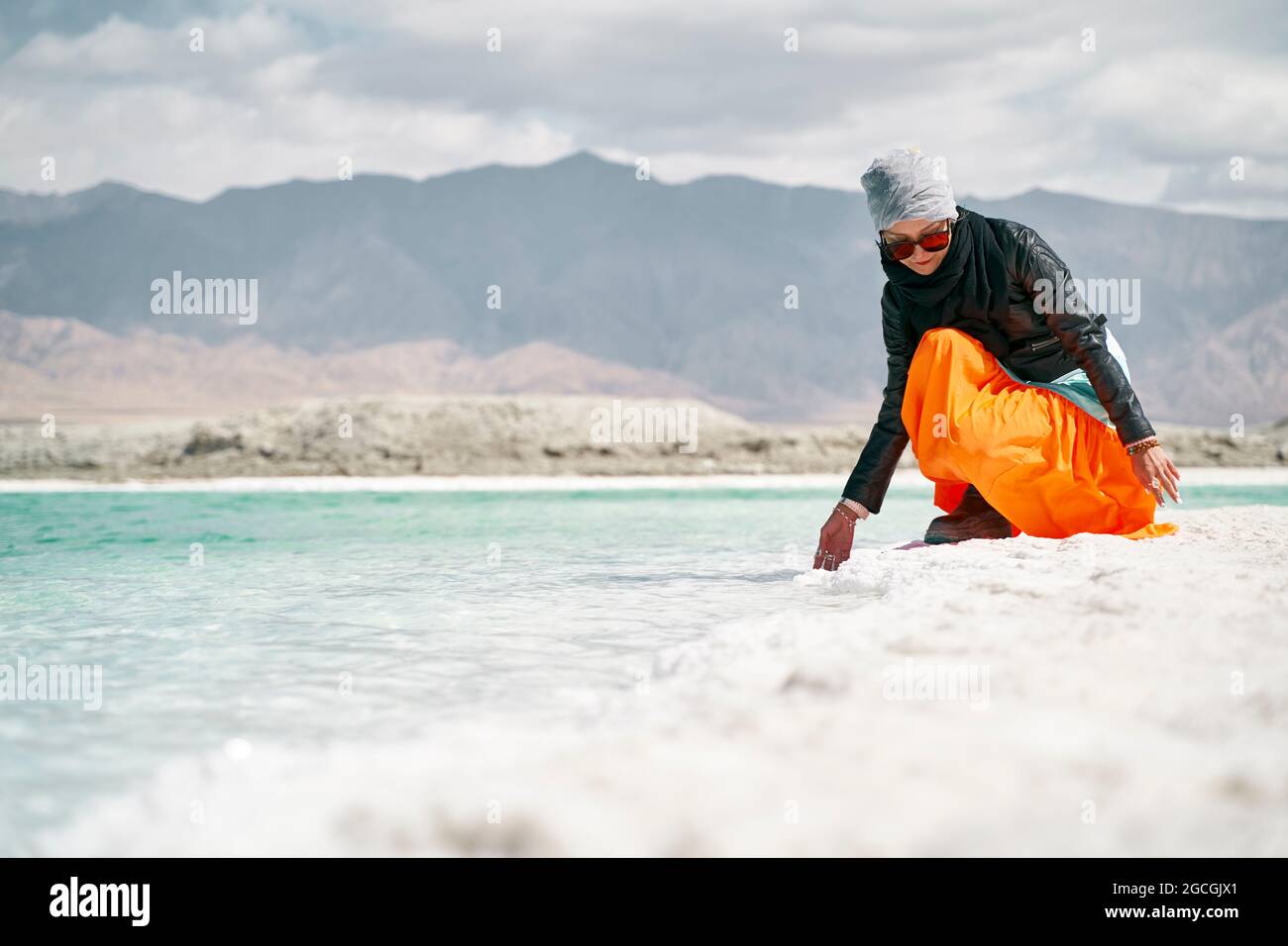 donna asiatica turista femminile che tocca l'acqua di un lago salato Foto Stock