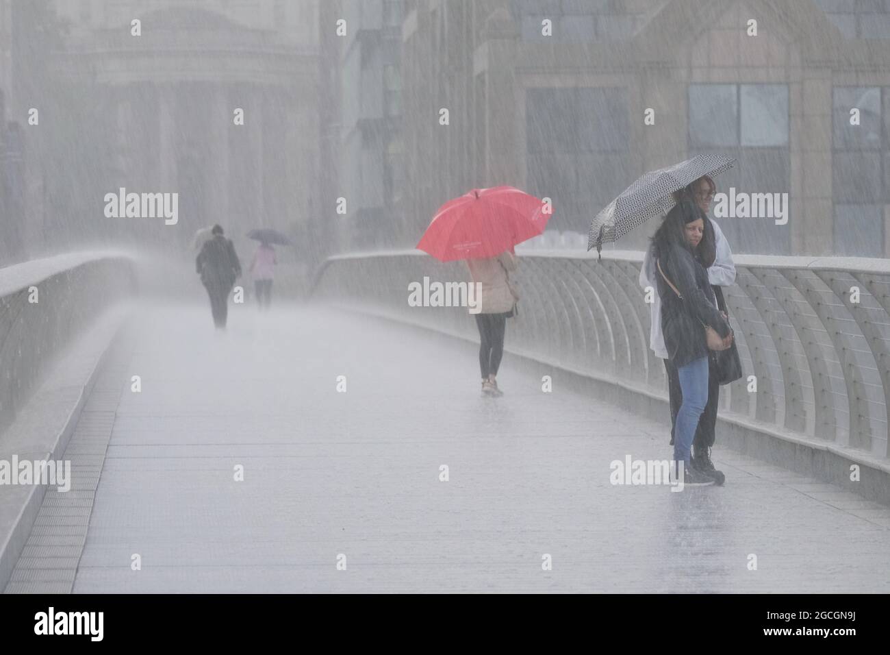 Londra, Regno Unito. Le persone sul Millennium Bridge portano gli ombrelli durante le piogge torrenziali che hanno causato un'inondazione di luce per alcune parti della capitale. Foto Stock