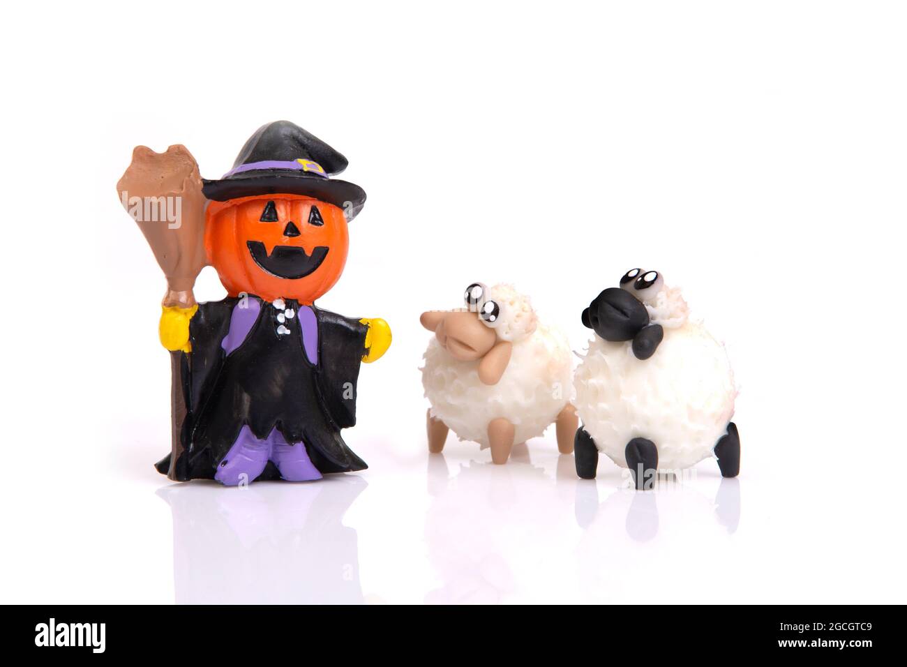 Piccola bambola di strega di zucca in ceramica con due pecore su sfondo bianco per la celebrazione dell'Halloween. Foto Stock