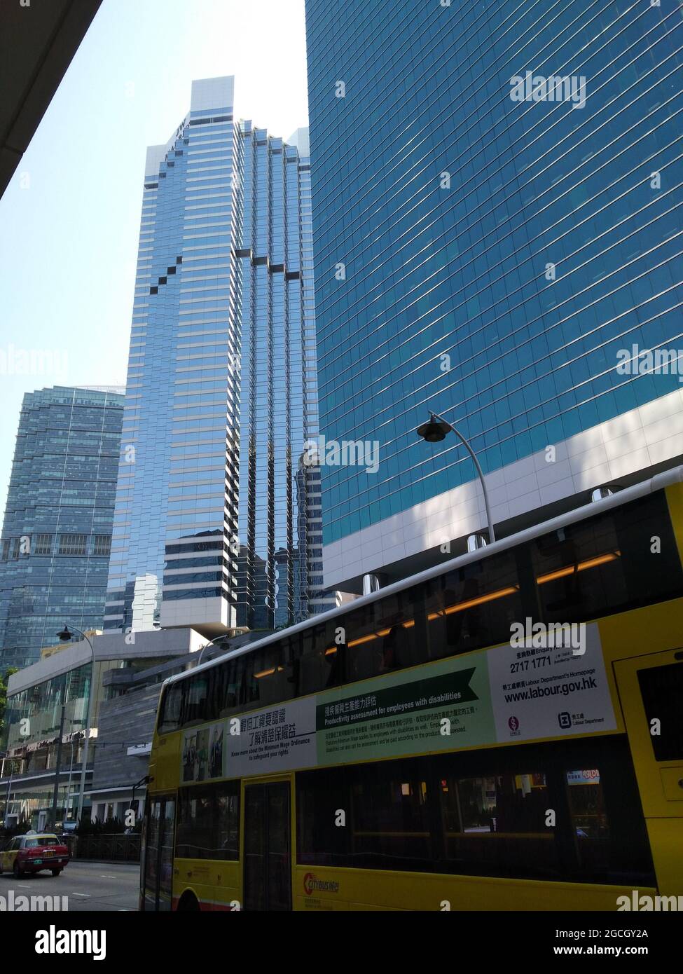 Un autobus cittadino a due piani nel centro di Admiralty di fronte a ricchi e moderni grattacieli nel quartiere degli affari. Foto Stock