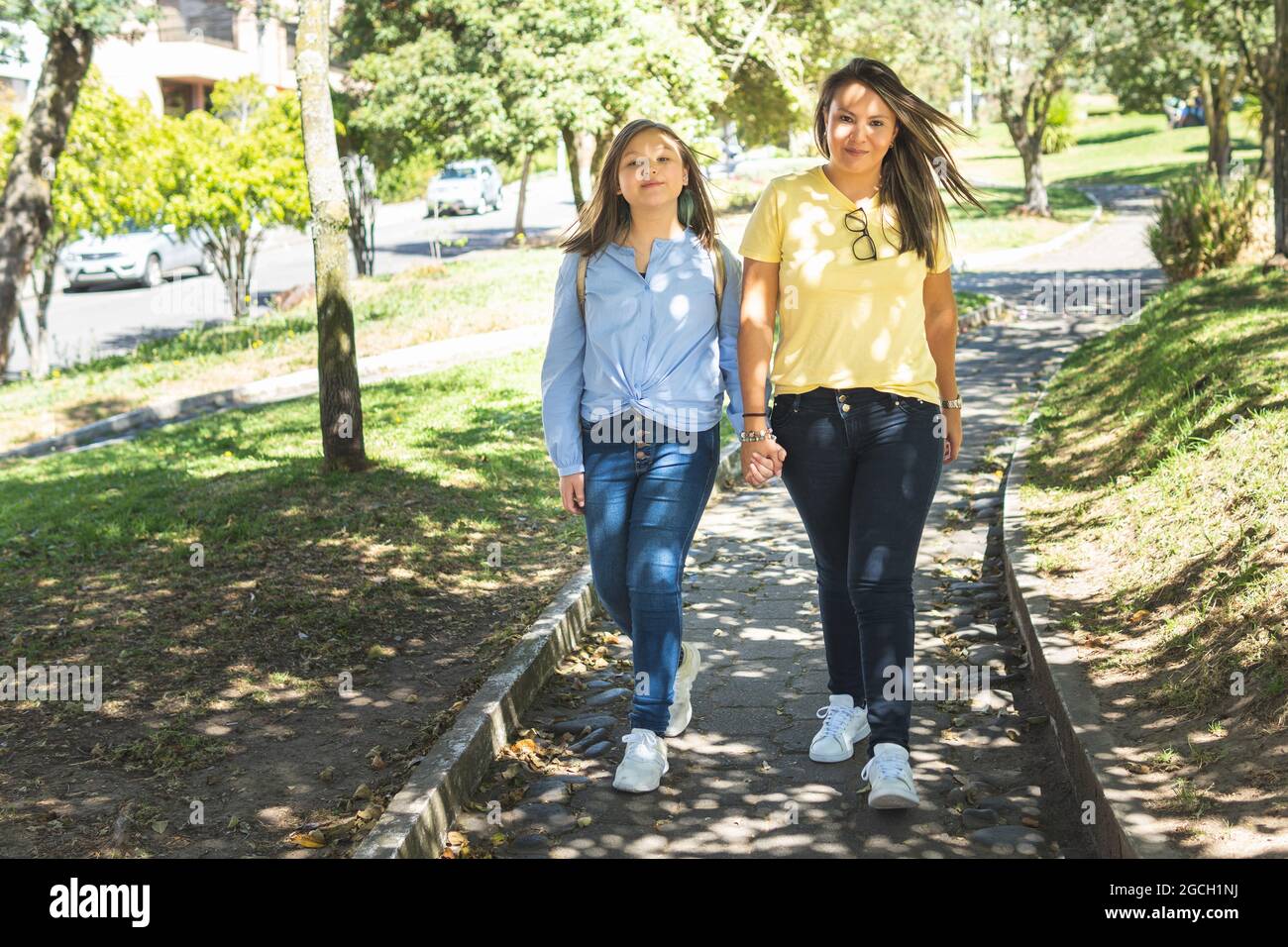 Madre e figlia sorridono sulla strada per la scuola. Ritorno a scuola Foto Stock