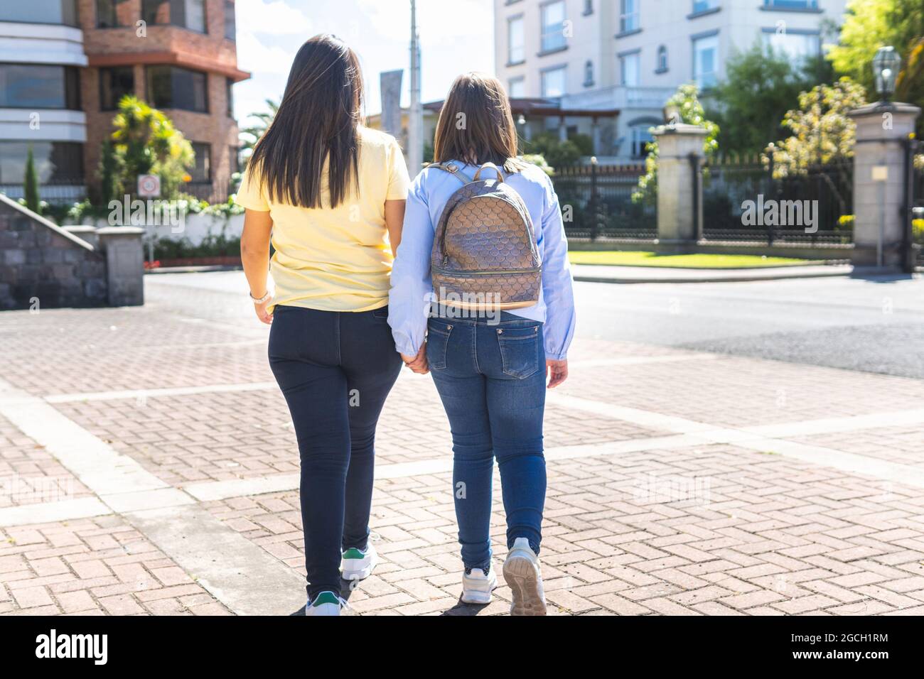 Fotografia di madre e figlia di nuovo a indietro camminando lungo il marciapiede verso la scuola Foto Stock