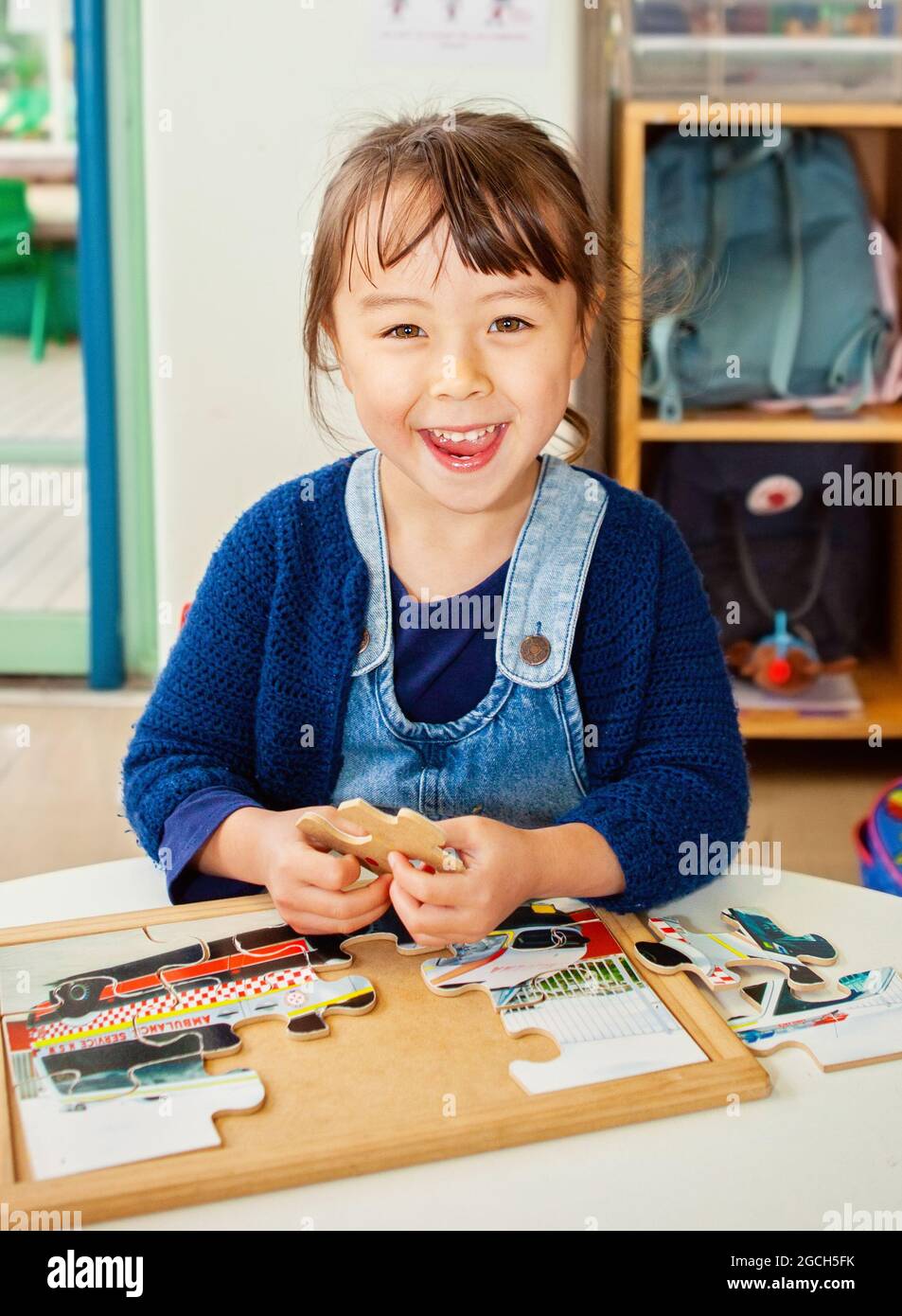 giovane ragazza seduta a un tavolo con un puzzle Foto Stock