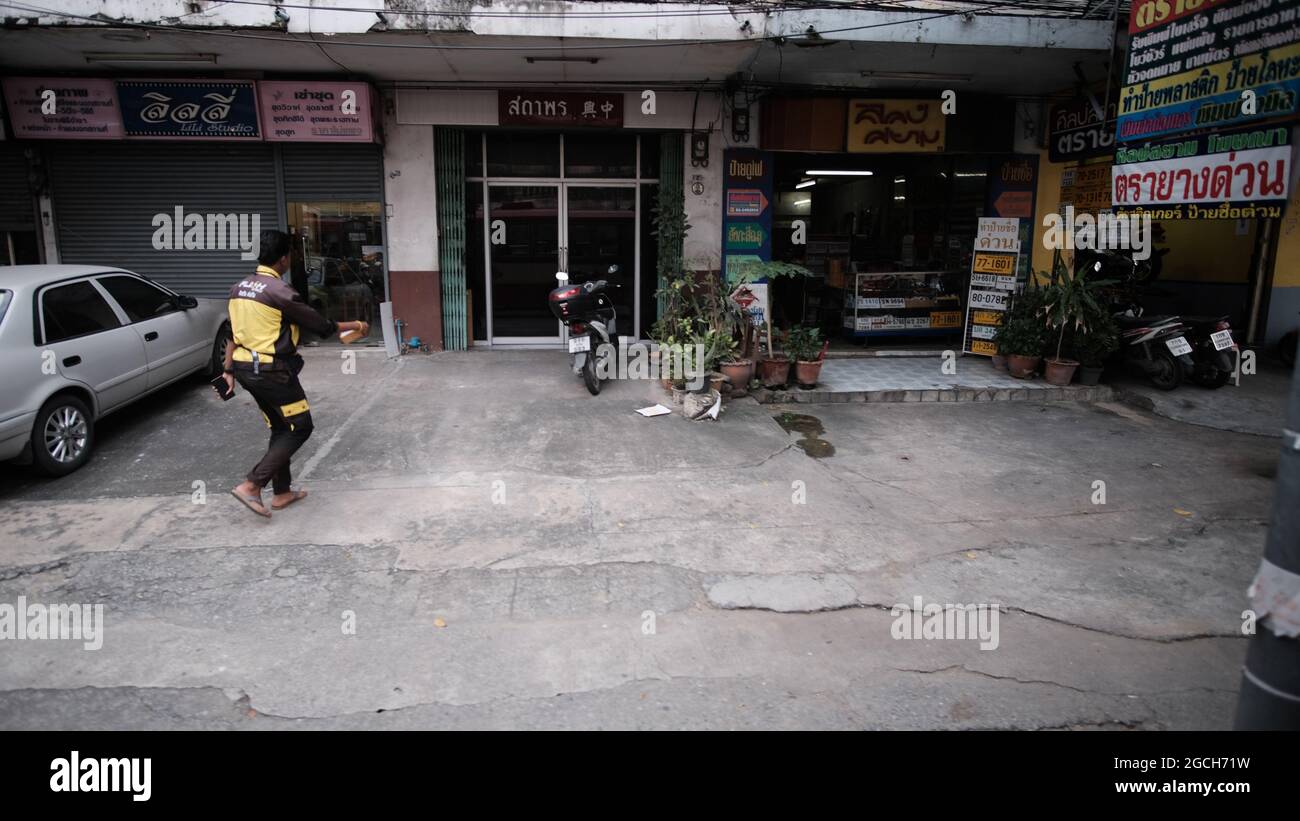 Uomo che cammina indossa un vestito nero e giallo con scarpe marroni Soi Ufficio postale Pattaya Thailandia Foto Stock