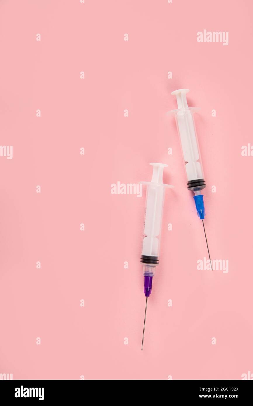 Siringhe poste su sfondo rosa. Concetto medico e vaccinazione. Vista dall'alto, disposizione piatta, spazio per la copia Foto Stock