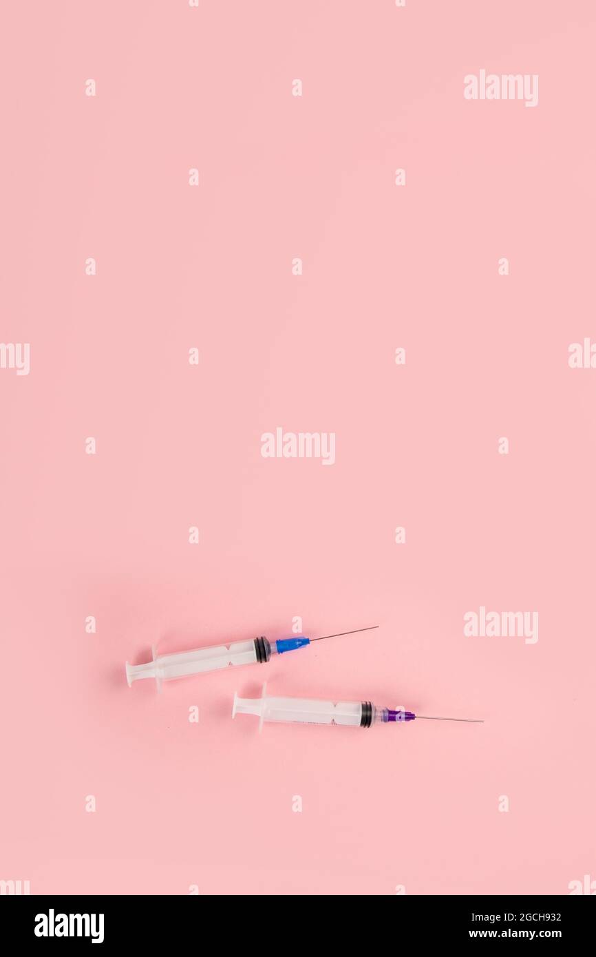 Siringhe poste su sfondo rosa. Concetto medico e vaccinazione. Vista dall'alto, disposizione piatta, spazio per la copia Foto Stock