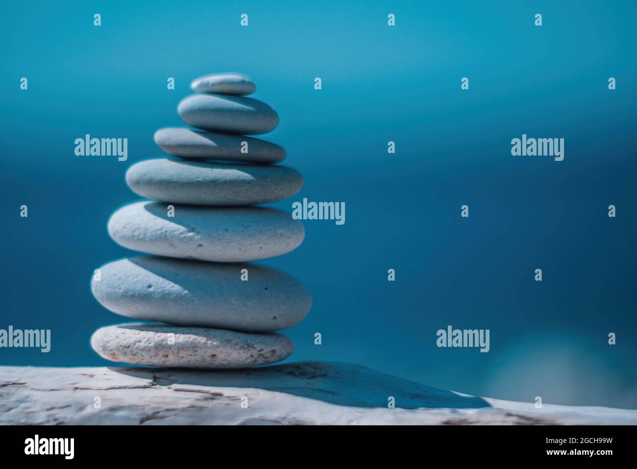 Equilibrata piramide di ciottoli sulla spiaggia in una giornata di sole. Abstract Sea bokeh sullo sfondo. Messa a fuoco selettiva. Pietre Zen sulla spiaggia di mare, meditazione Foto Stock