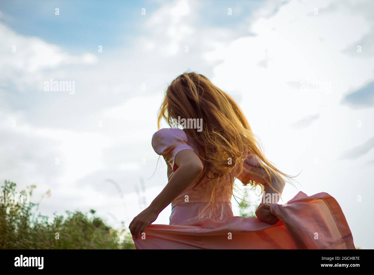 ragazza che corre sul campo in un vestito rosa Foto Stock