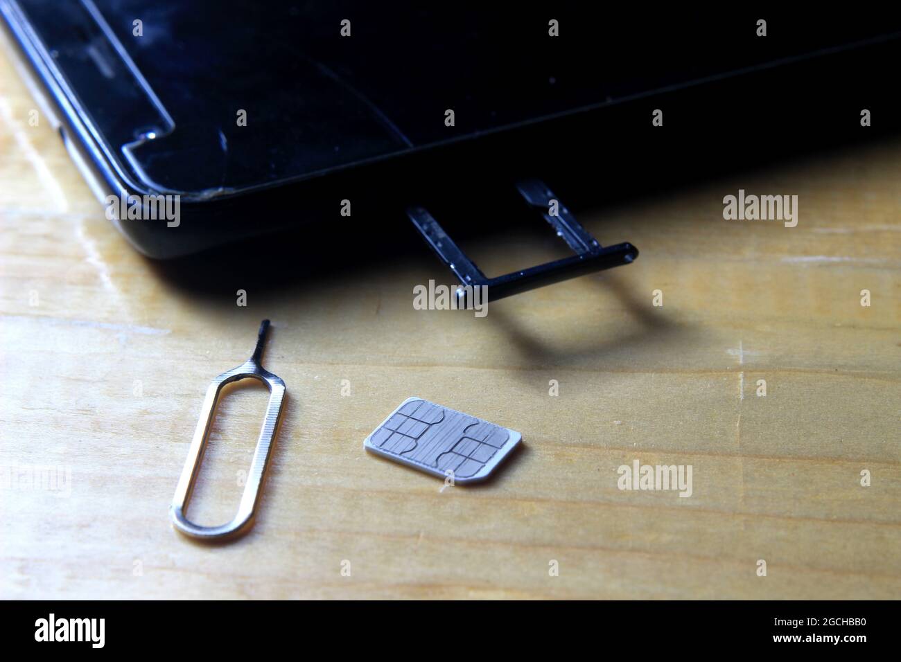 Scheda SIM estrattore e smartphone al tavolo di legno Foto Stock