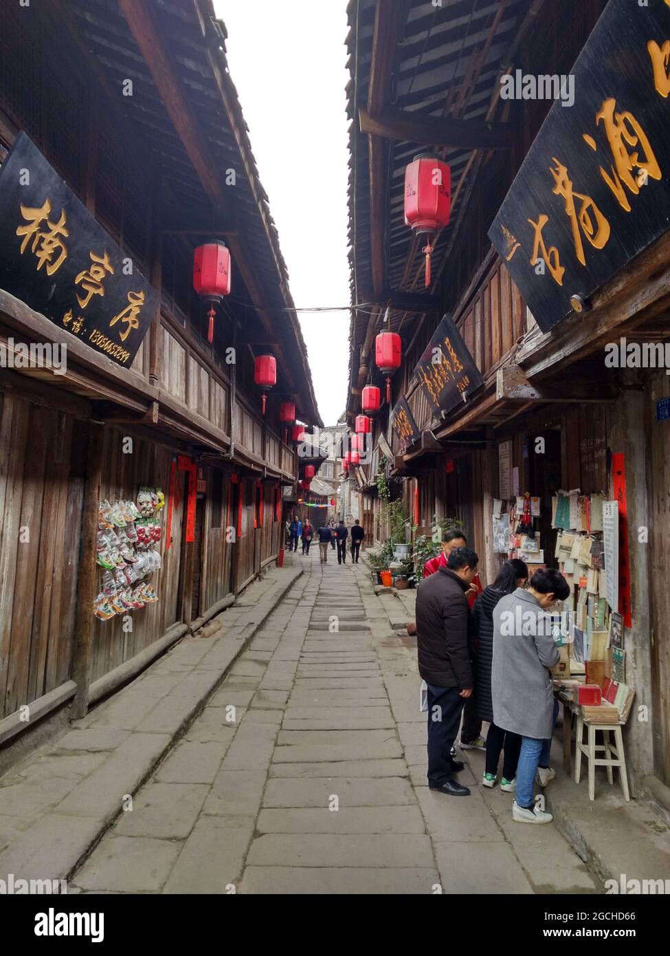 Persone al di fuori dei negozi turistici locali nell'antico quartiere del mercato di Lizhuang con vecchi edifici e belle insegne in legno intagliato Foto Stock