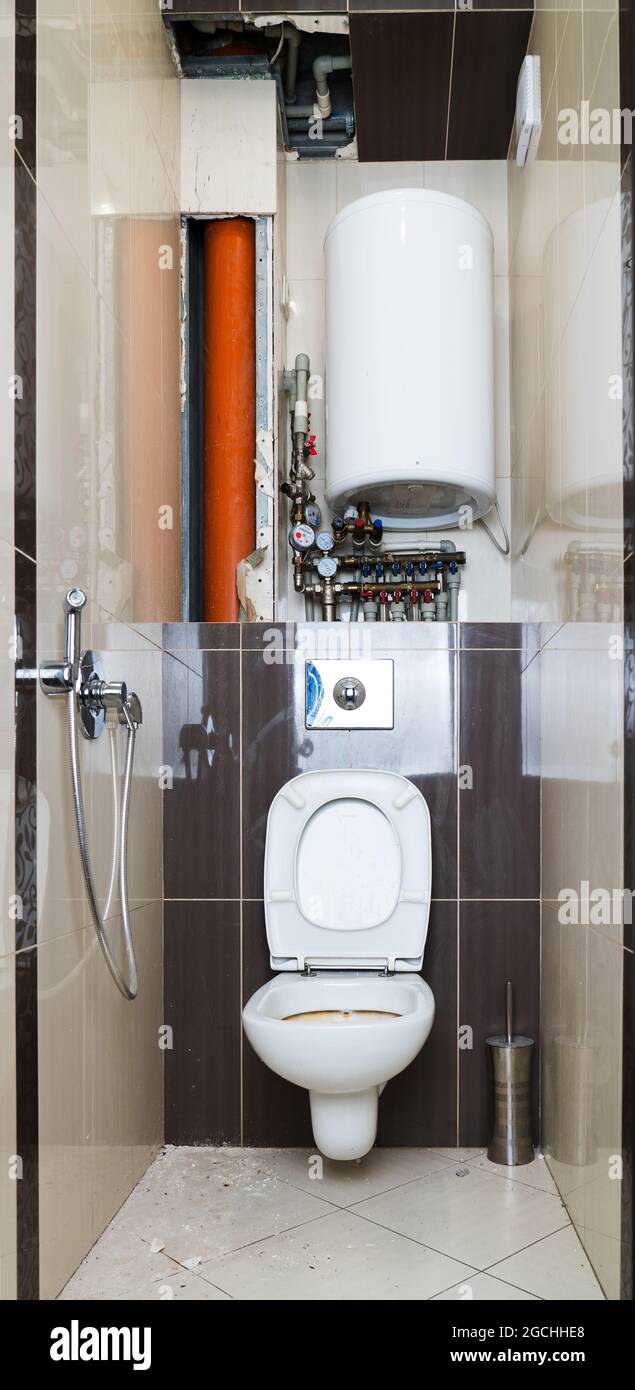 riparazione toilette. Toilette con piastrelle rimosse a causa della necessità di sostituire il montante e tubi. Sistema di tubazioni complesso, parete telaio appeso, collettore idraulico, bo Foto Stock