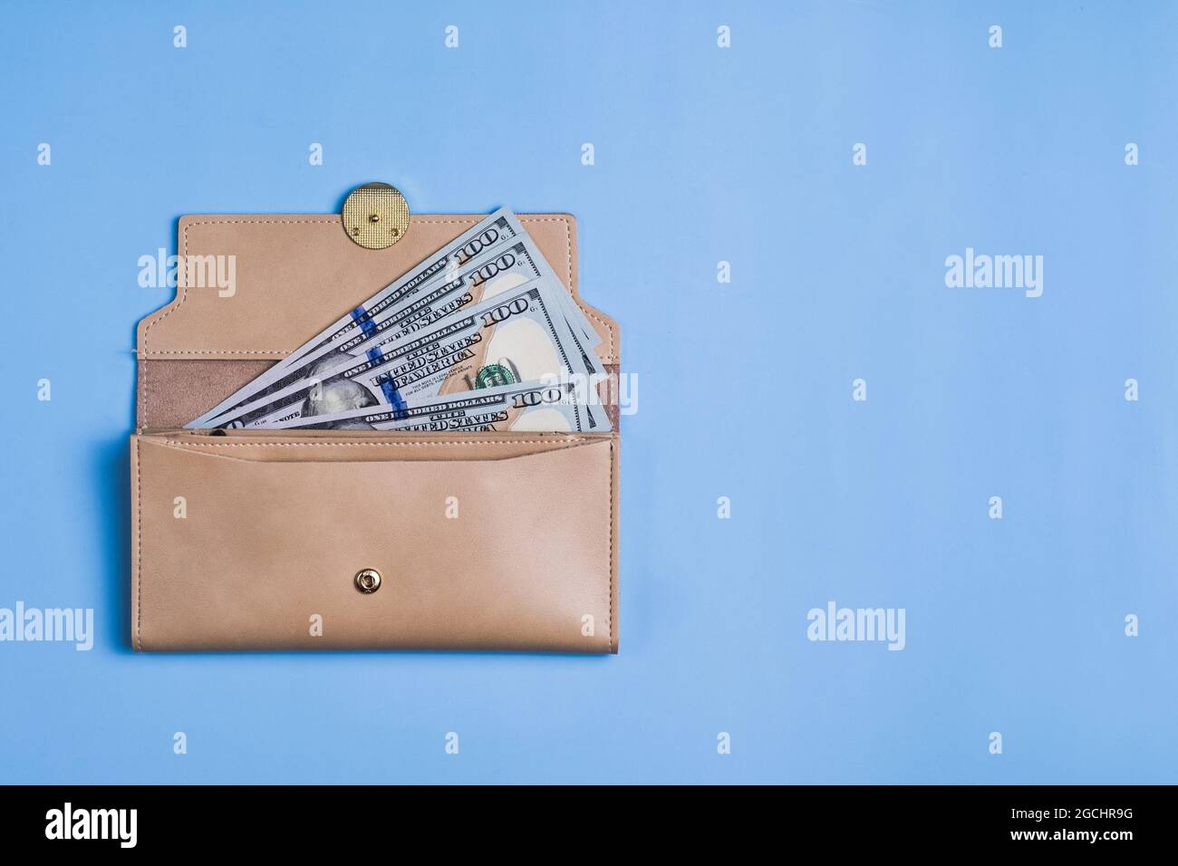 Banconote da 100 dollari con e portafoglio su sfondo blu. Foto Stock