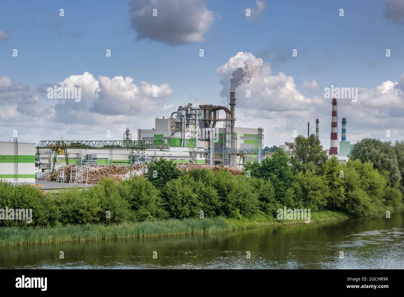 tubi di legno impresa segheria pianta vicino fiume. Concetto di inquinamento dell'aria. Paesaggio industriale inquinamento ambientale spreco di energia termica p Foto Stock