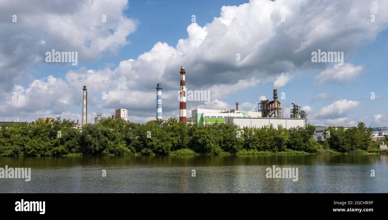 tubi di legno impresa segheria pianta vicino fiume. Concetto di inquinamento dell'aria. Paesaggio industriale inquinamento ambientale spreco di energia termica p Foto Stock