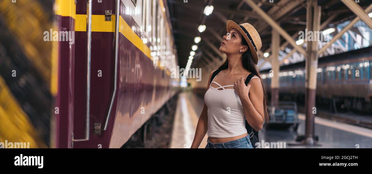 Giovane e sicura donna con bruna ispanica che guarda la carrozza ferroviaria sulla piattaforma della stazione Foto Stock