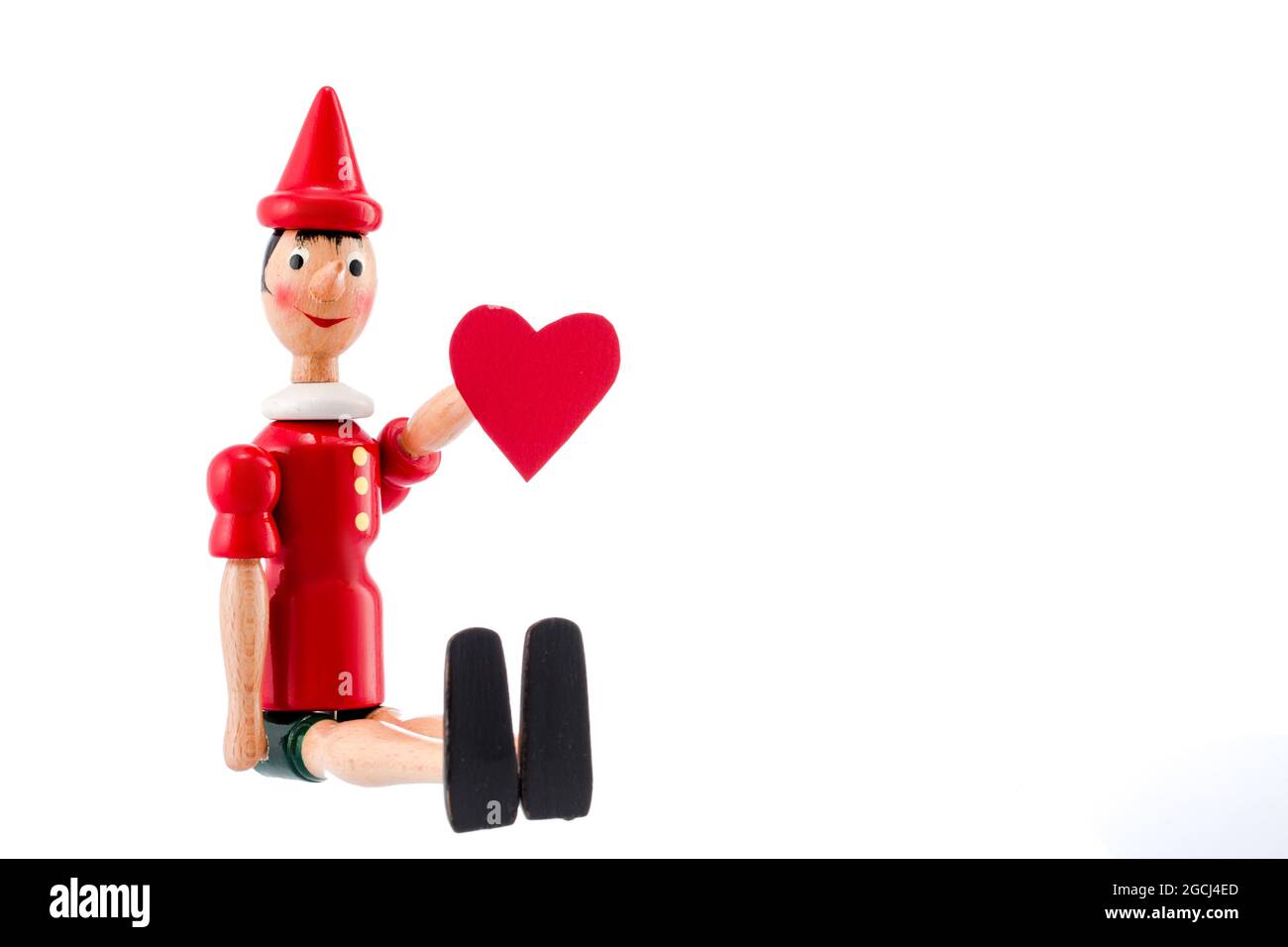 Pinocchio toy statua e cuore isolato su sfondo bianco. Il giorno di San Valentino del concetto. Foto Stock