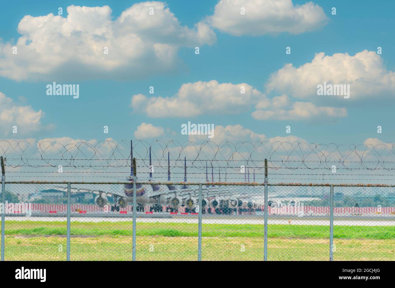 Recinzione metallica dell'aeroporto e aereo blur parcheggiato presso l'area parcheggio dell'aeroporto. Molti aerei parcheggiati e voli impatto da un coronavirus. Foto Stock