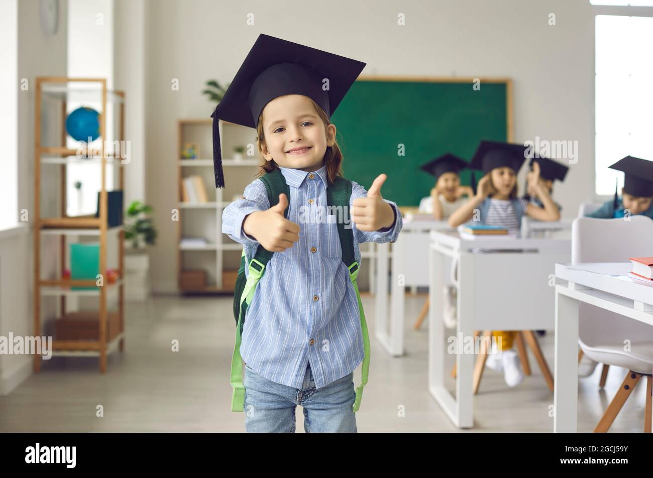 Il ragazzo sta indossando un tappo di graduazione, mostrando i pollici verso l'alto. Foto Stock