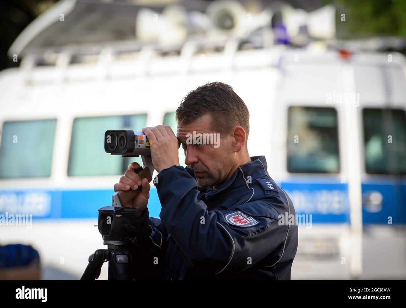 09 agosto 2021, Brandeburgo, Potsdam: Il sovrintendente capo della polizia Radtke controlla la velocità dei veicoli su Yorckstraße, che è designato per la velocità 30, presso la scuola primaria Max-Dortu mediante misurazione laser. Nei primi quaranta giorni dopo l'inizio della scuola dopo le vacanze estive, la polizia intende intensificare i controlli del traffico in tempi prioritari. Allo stesso tempo, la campagna di sicurezza del traffico 'Lieber sicher. Lieber leben.' è stato lanciato per promuovere la considerazione tra ciclisti e autisti e per educare bambini e genitori sulla sicurezza stradale. Foto: Soeren Stache/dpa-Zentralbild/dpa Foto Stock