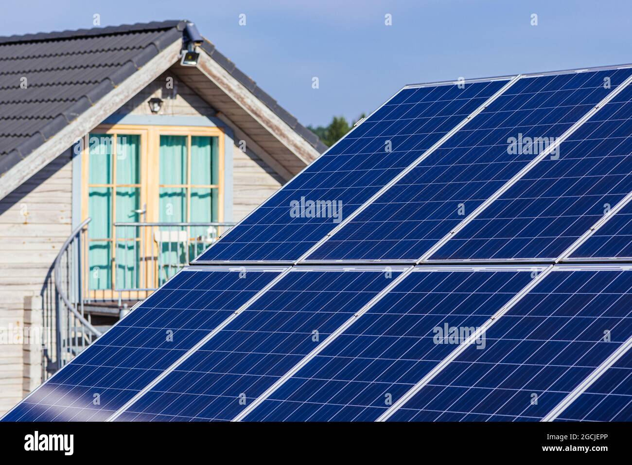 Pannelli solari sul campo in campagna con casa sullo sfondo. Impianto solare. Pannelli solari blu. Fonte alternativa di elettricità. Solare Foto Stock
